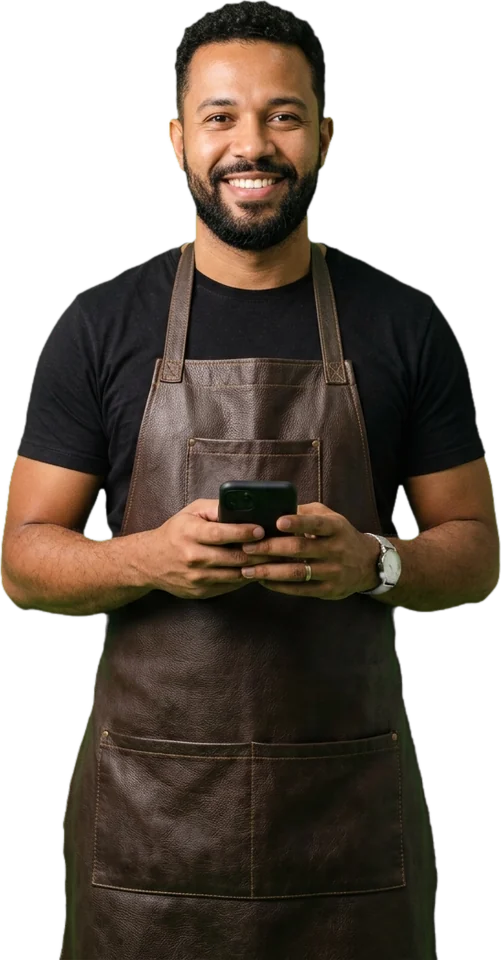 Barbeiro de avental de couro segurando o celular, sorrindo
